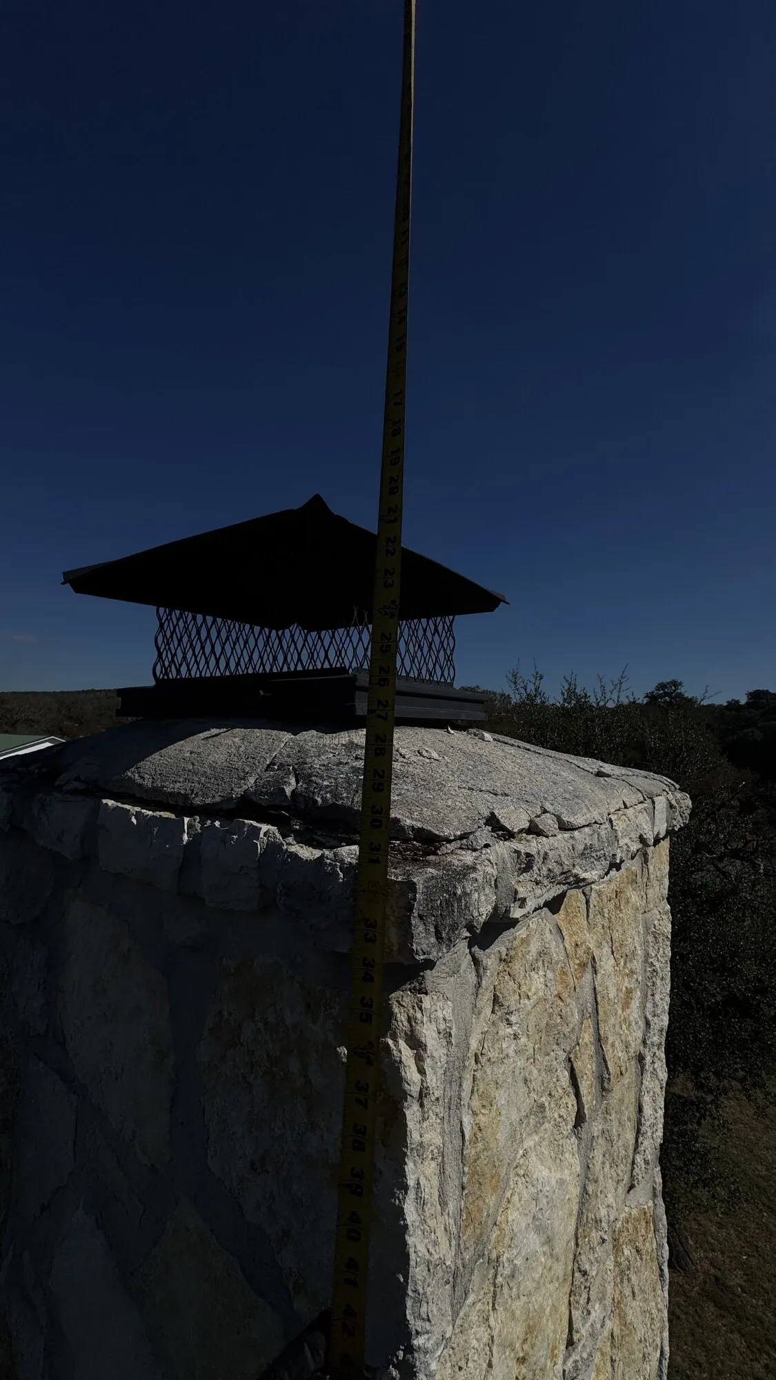 Chimney cap inspection — elevated metal rain cover